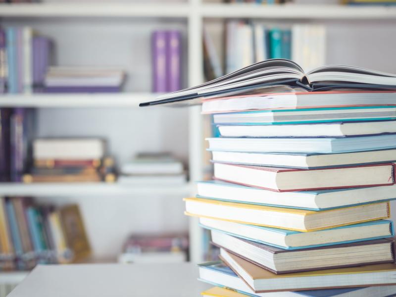 Bøger i en bunke og bøger i baggrunden på hylder